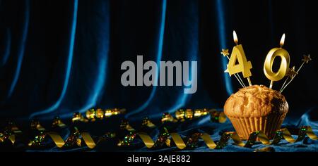 Numero 40 di candele per festeggiare l'oro e piccole stelle in dolce cupcake su sfondo blu brillante in velluto. Concetto di celebrare il compleanno, l'anniversario Foto Stock