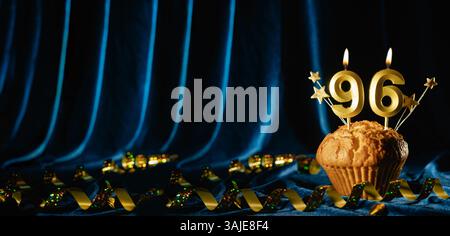 Numero 96 di candele per festeggiare l'oro e piccole stelle in dolce cupcake su sfondo blu brillante in velluto. Concetto di celebrare il compleanno, l'anniversario Foto Stock