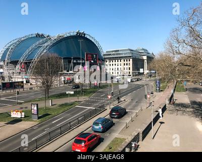 Colonia, Germania - 22 marzo 2022 - strada trafficata con un grande stadio sullo sfondo. La strada è piena di auto e persone, e CE ne sono Foto Stock