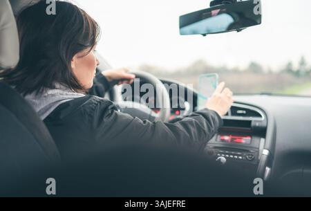 Donna si prepara a Un lungo viaggio in auto impostando il percorso mappa sul navigatore GPS sullo smartphone Foto Stock