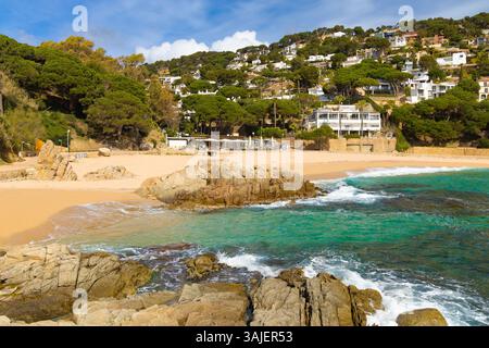 Vista panoramica della spiaggia di Cala Sant Francesc a Blanes, con acqua turchese, sabbia dorata, costa rocciosa e case in collina. Foto Stock