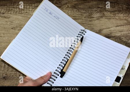 Pagina del blocco appunti vuota con la mano e la penna elenco delle attività Foto Stock