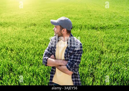 Agricoltore maschio con le braccia incrociate in un campo di grano invernale all'inizio della primavera Foto Stock