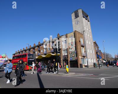 Central Parade con torre dell'orologio, una sfilata di negozi di livello II costruita alla fine degli anni '1950 con appartamenti e uffici sopra le unità di vendita al dettaglio di Walthamstow, Londra, Regno Unito Foto Stock