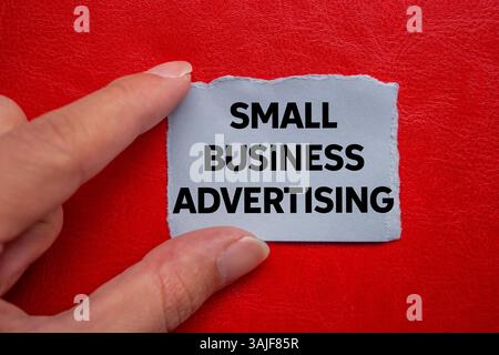 Small business advertising message written on ripped torn grey paper piece on red background. Conceptual small business advertising symbol. Copy space Foto Stock
