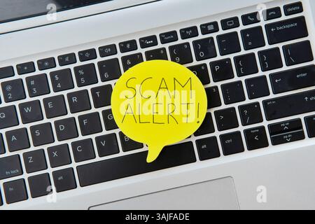 Bolla vocale gialla sulla parte superiore della tastiera del notebook con AVVISO DI TRUFFA testuale. Concetto tecnologico. Foto Stock