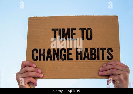 Messaggio "tempo per cambiare abitudini" scritto su un cartello di cartone. Simbolo del tempo concettuale per cambiare le abitudini. Copia spazio. Foto Stock