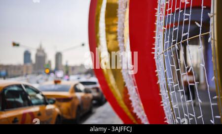 Decorazioni natalizie che incorniciano il paesaggio urbano di Mosca offuscato con taxi gialli in attesa nel traffico Foto Stock
