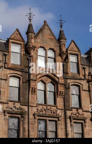 Le distese bionde in arenaria di Broomhill Drive, Glasgow, mostrano i dettagli di alcune delle pietre scolpite e delle torrette durante il sole primaverile Foto Stock