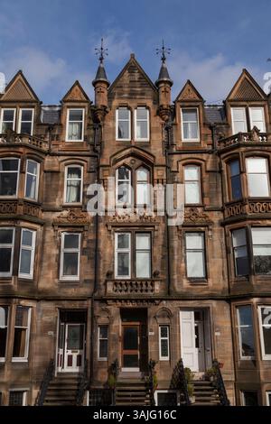 Le distese bionde in arenaria di Broomhill Drive, Glasgow, mostrano i dettagli di alcune delle pietre scolpite e delle torrette durante il sole primaverile Foto Stock