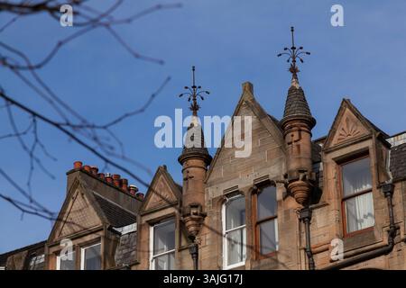 Le distese bionde in arenaria di Broomhill Drive, Glasgow, mostrano i dettagli di alcune delle pietre scolpite e delle torrette durante il sole primaverile Foto Stock