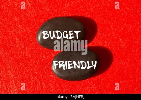Messaggio economico scritto su pietre nere su sfondo rosso. Simbolo di budget concettuale. Copia spazio. Foto Stock