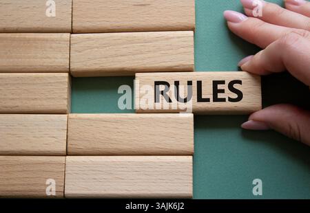 Simbolo delle regole. Blocchi di legno con la parola regole. Mano d'affari. Splendido sfondo grigio/verde. Concetto di regole. Copia spazio. Foto Stock