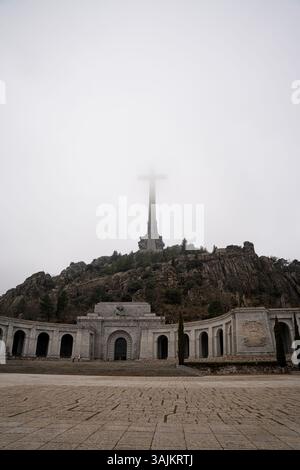 La maestosa Valle de los Caídos Cross è circondata dalle montagne nebbiose Foto Stock