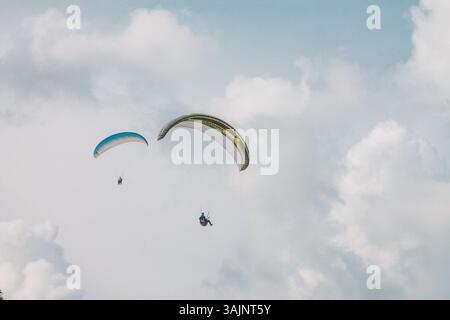 Due parapendio sorvolano i cieli delle Filippine, mostrando avventura, libertà e viste aeree mozzafiato su uno sfondo nuvoloso Foto Stock