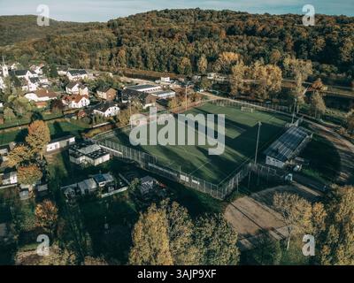 Una splendida vista aerea di un affascinante villaggio vicino al fiume Mosella, Lussemburgo, che mostra un vivace campo da calcio circondato da case residenziali Foto Stock