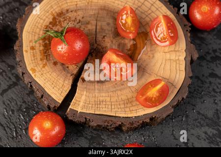 pomodori rossi tagliati a fette su una tavola di noci, diversi pomodori rossi maturi durante la cottura, su una fetta di legno di noce da vicino, vista dall'alto, vista laterale Foto Stock