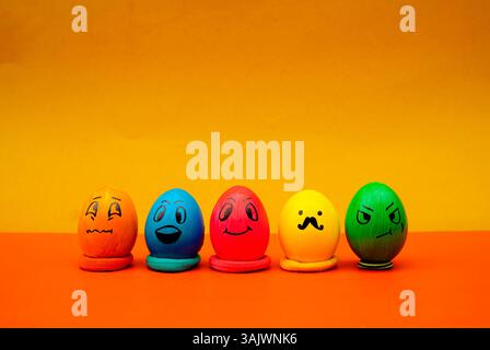 Uova di emoji colorate in fila per una foto allegra e giocosa di Pasqua. Volti creativi dell'uovo di Pasqua con espressioni divertenti Foto Stock