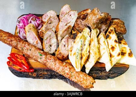 Una vivace mostra di varie carni alla griglia, tra cui spiedini, salsicce e pane servito insieme a cipolle fresche e peperoni, che mostrano un ricco culinario Foto Stock