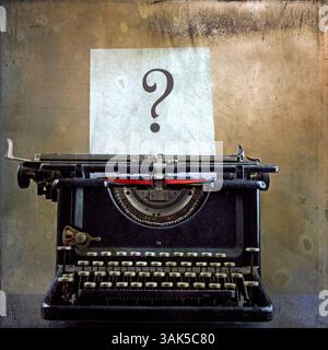 Una macchina da scrivere d'epoca si trova in un'atmosfera rustica, mostrando un foglio bianco con un importante punto interrogativo. Foto Stock