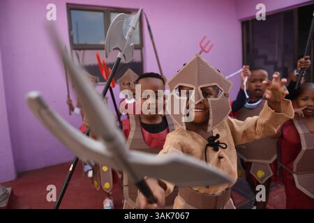 La produzione della passione di Cristo in Sud Africa i ragazzi sudafricani si preparano ad esibirsi in una produzione intitolata la sfilata della passione di Cristo, una collaborazione tra la scuola di sviluppo della prima infanzia ECD Kiddies Hope Academy e la Nkosana Ngobese Foundation attraverso le strade di Dobsonville, Soweto, Sud Africa 12 aprile 2025. La passione della produzione di Cristo è una rappresentazione drammatica dell'ultimo giorno della vita di Gesù, culminante nella crocifissione. La produzione presentava bambini di 5 e 6 anni in costumi, vestiti da angeli, Gesù con una croce e soldati romani, oltre a un gigante Foto Stock