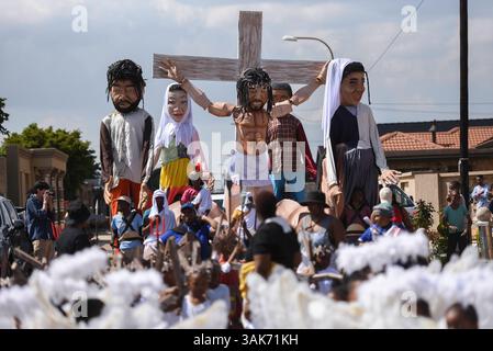 The Passion of the Christ Production in Sud Africa i partecipanti partecipano alla Passion of the Christ Parade, una collaborazione tra la scuola ECD per lo sviluppo della prima infanzia Kiddies Hope Academy e la Nkosana Ngobese Foundation attraverso le strade di Dobsonville, Soweto, Sud Africa 12 aprile 2025. La passione della produzione di Cristo è una rappresentazione drammatica dell'ultimo giorno della vita di Gesù, culminante nella crocifissione. La produzione presentava bambini di 5 e 6 anni in costumi, vestiti da angeli, Gesù che trasportava una croce e soldati romani, oltre a marionette giganti che interpretavano il ruolo di Jesu Foto Stock