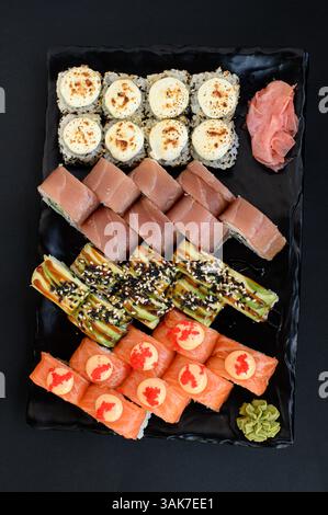 Un variopinto assortimento di sushi con panini con avocado, salmone e tonno, presentati in uno stile pulito e moderno. Foto Stock