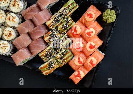 Un variopinto assortimento di sushi con panini con avocado, salmone e tonno, presentati in uno stile pulito e moderno. Foto Stock
