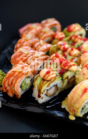 Un variopinto assortimento di sushi con panini con avocado, salmone e tonno, presentati in uno stile pulito e moderno. Foto Stock