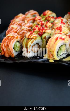Un variopinto assortimento di sushi con panini con avocado, salmone e tonno, presentati in uno stile pulito e moderno. Foto Stock