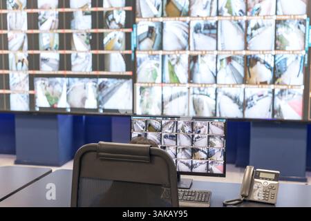 Agente di sicurezza che monitora più schermi di sorveglianza in una sala di controllo high-tech per la sicurezza e la sorveglianza Foto Stock
