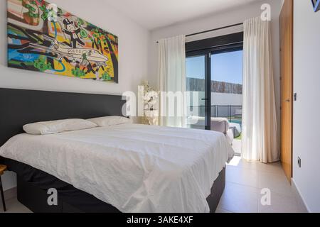 Camera luminosa con accesso diretto al giardino, con letto grande, tela Street art e luce naturale attraverso porte in vetro. Foto Stock