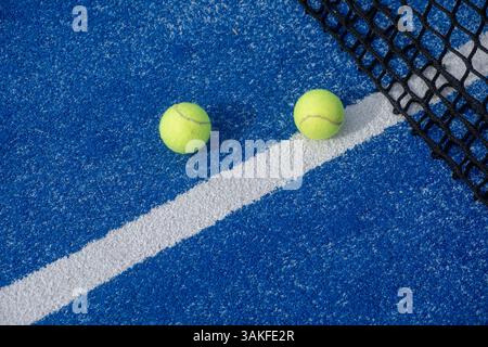due palline di padel vicino alla rete in un campo da paddle tennis blu, sfondo per racquetball sport Foto Stock