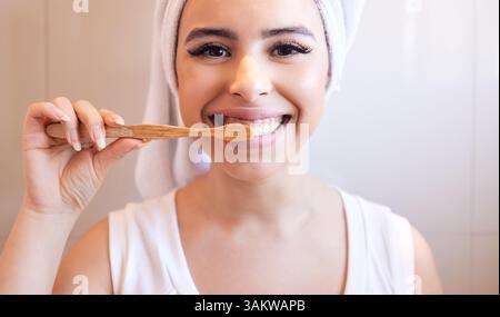 Bagno, ritratto o donna felice spazzolando i denti con il prodotto in bambù per una sana igiene orale. Ecocompatibile, casa e ragazza che puliscono la bocca Foto Stock