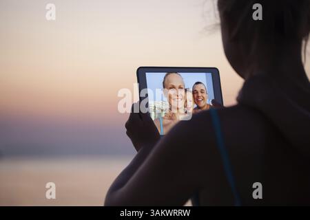 Madre, padre e figlio facendo selfie utilizzando computer tablet. Essi prendendo immagine sullo sfondo resort Foto Stock