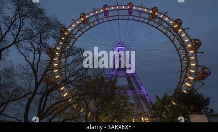Scatto ad angolo basso della ruota panoramica illuminata a Vienna, Austria. Osservare la città dall'alto Foto Stock