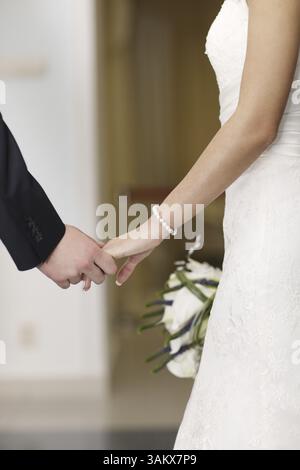 Sposa e lo sposo tenendo le mani come stanno facendo i loro voti di amore e impegno in vista ingrandita delle loro mani giunte Foto Stock
