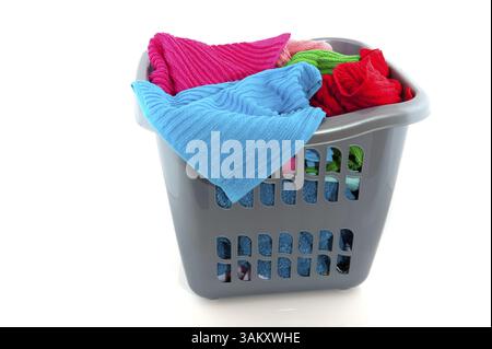 Cestino per bucato pieno di asciugamani colorati, isolato su bianco Foto Stock
