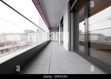 Moderno balcone cittadino con ringhiera in vetro e vista sulla costruzione urbana Foto Stock