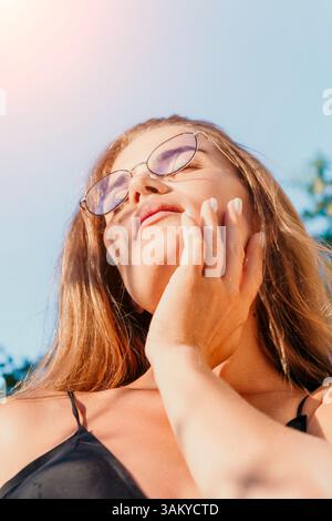 Occhiali da sole donna Sun Outdoor - Ritratto di una donna che indossa occhiali da sole, che guarda il sole mentre è all'aperto. Foto Stock