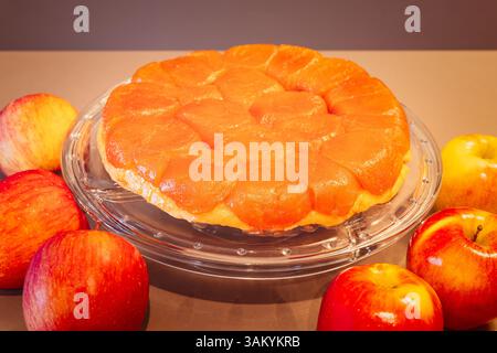 Tarte Tatin di mele in crosta dorata con scintillante guarnizione di frutta fotografata in stile rivista retrò con mele rosse e gialle intorno Foto Stock