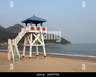 Torre bagnino situata sulla spiaggia con splendide montagne panoramiche sullo sfondo Foto Stock