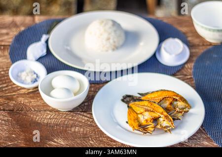 Una colazione tradizionale filippina a base di riso, pesce secco e uova sode servite fresche a Isla Gigantes, Iloilo Foto Stock