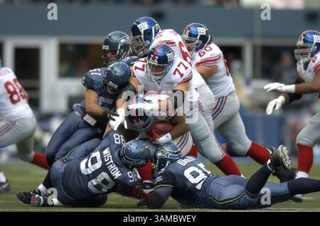 27 novembre 2005 - Seattle, WA, USA - il runningback dei New York Giants Tiki Barber (21) viene fermato per una sconfitta dai difensori dei Seattle Seahawk Lofa Tatupu (51), Grant Wistrom (98) e Rodney Bailey (95) durante la prima metà della domenica al Qwest Field di Seattle, Washington. I Seahawks batterono i Giants 24-21 ai tempi supplementari. 27 novembre 2005. ©Troy Wayrynen/Columbian

 (immagine di credito: © Troy Wayryen/ZUMAPRESS.com) Foto Stock
