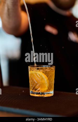Il barman versa un cocktail da una bottiglia in un bicchiere. Foto Stock