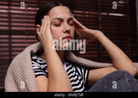 Donna depressa avvolta in plaid a casa Foto Stock