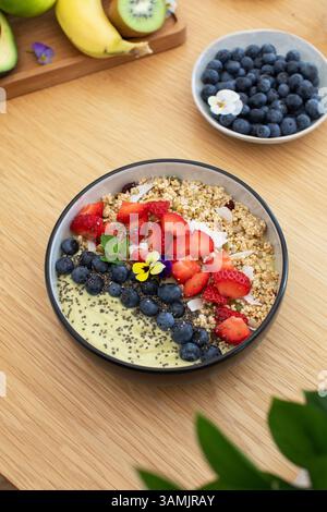 Sana prima colazione con frullato di avocado con frutta fresca e semi di chia su un tavolo di legno Foto Stock