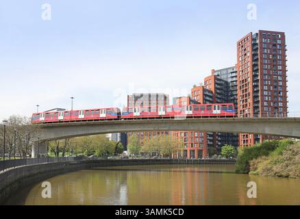 London, UK, il treno della Docklands Light Railway attraversa il fiume Lea/Bow Creek verso Canning Town. Murcury Walk sviluppo degli alloggi in background. Foto Stock