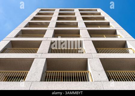 Vista prospettica del moderno edificio di appartamenti in cemento in Polonia con ringhiere gialle e finestre ripetitive Foto Stock
