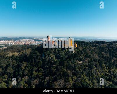 Vista aerea del bellissimo Palazzo Nazionale di pena circondato da una lussureggiante foresta e maestose montagne, Sintra, Lisbona, Portogallo. Foto Stock